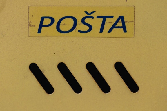 Жълта метална пощенска кутия със син надпис на пощата