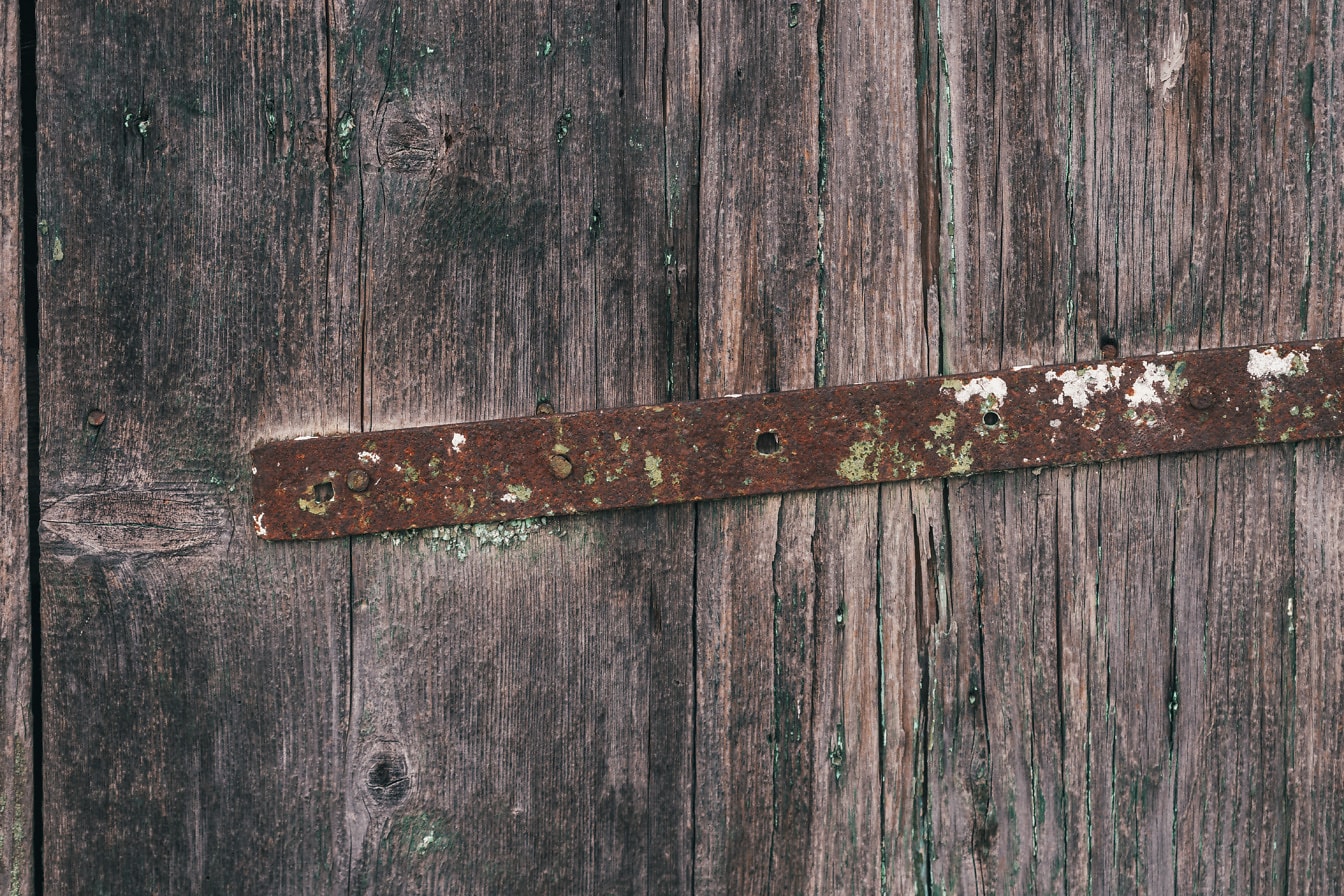 Roestige metalen versteviging op oude houten deuren