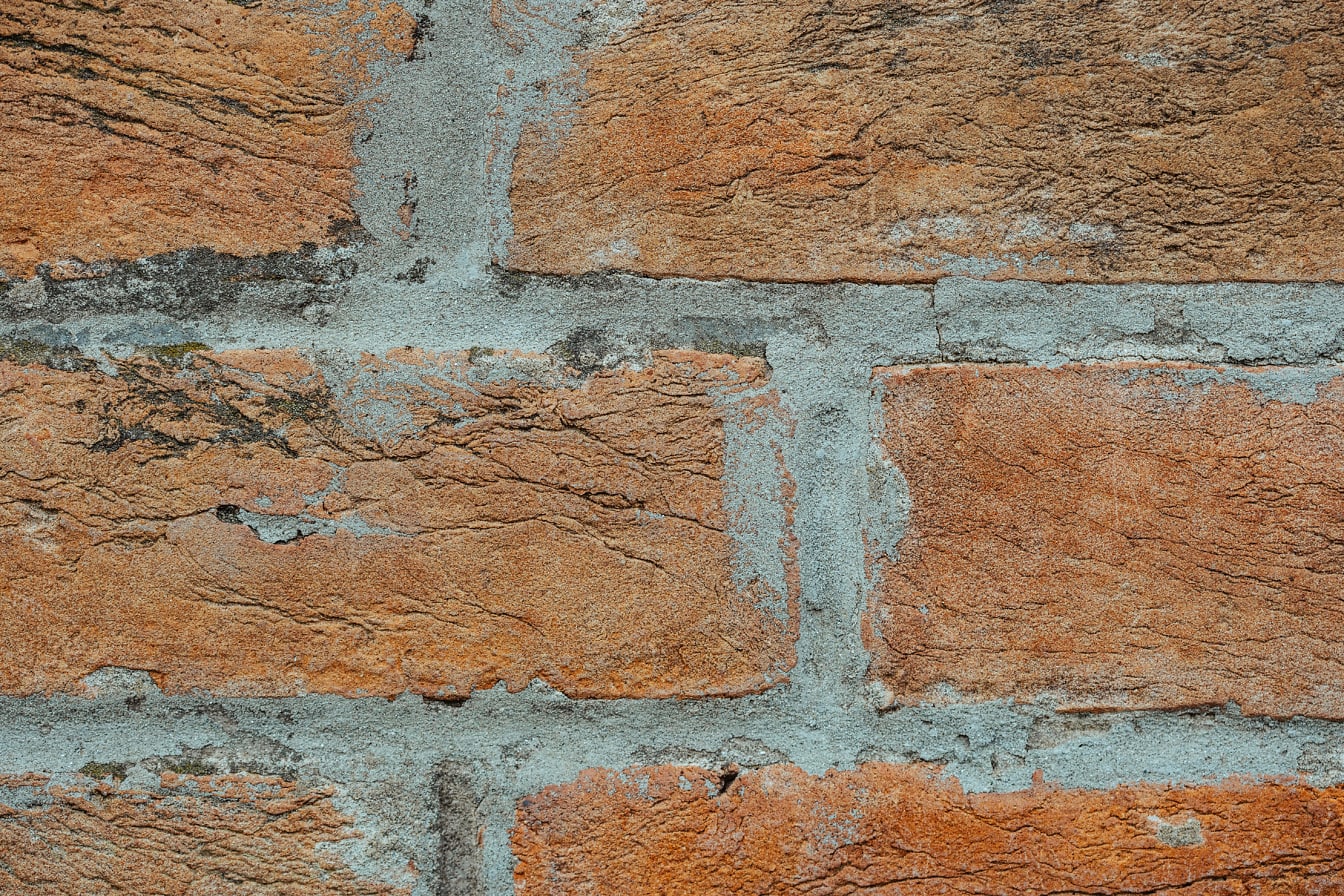 Een gewone bakstenen muur met horizontaal gestapelde bakstenen en grijs cement
