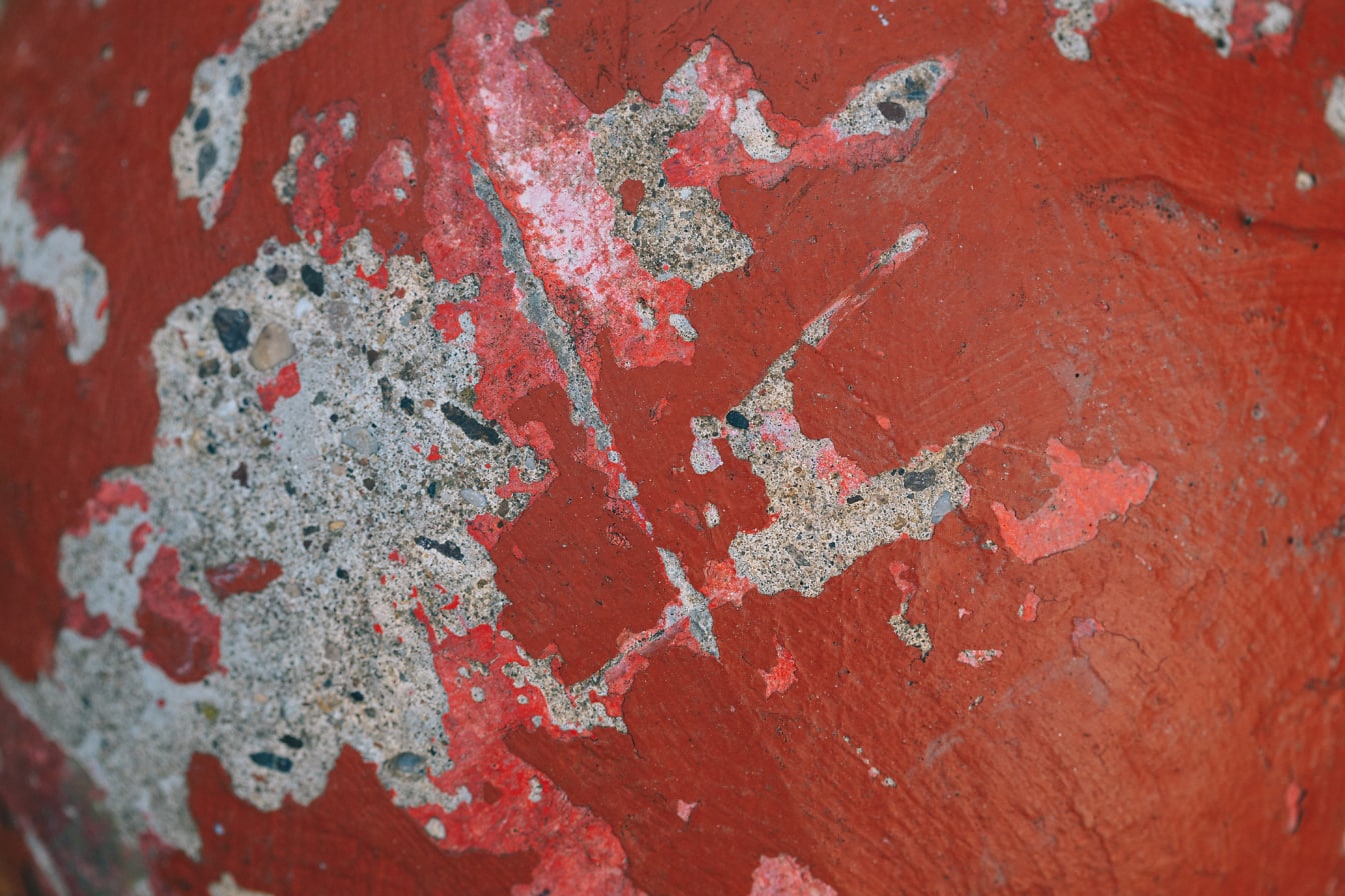 Vieille peinture rouge qui s’écaille du béton