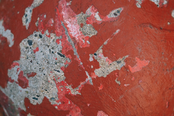 Old red paint peeling off from concrete