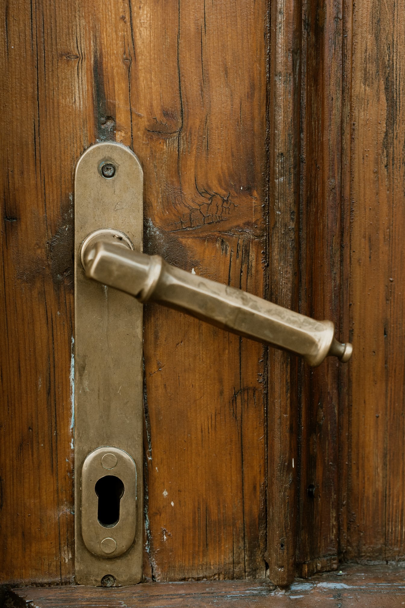 Close-up da maçaneta da porta antiga em uma porta da frente de madeira de lei