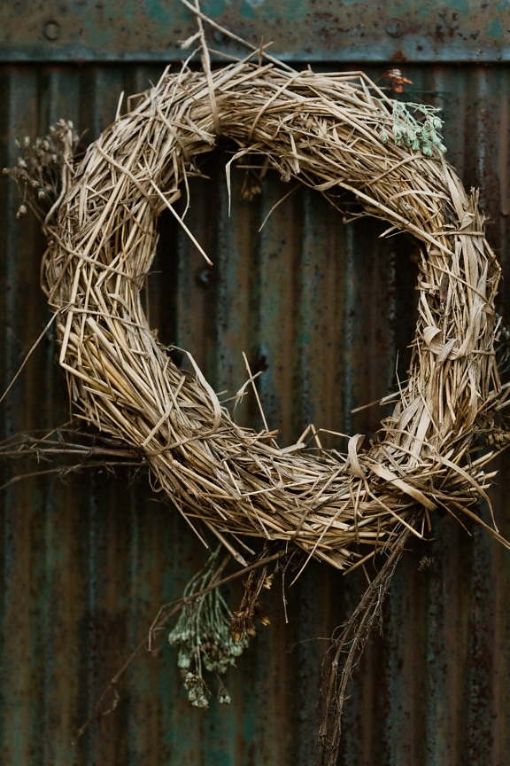 Dry handmade wreath on old rusty metal door