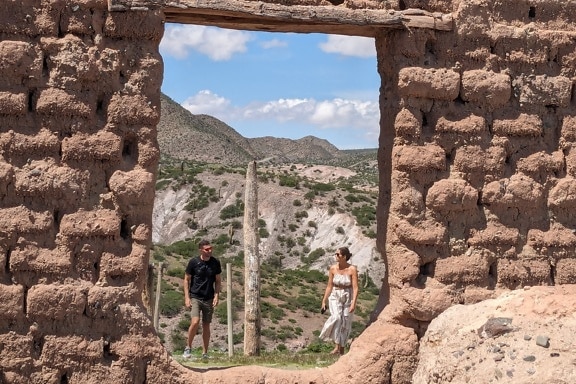 Руины дверного проема на переднем плане с мужчиной и женщиной на заднем плане