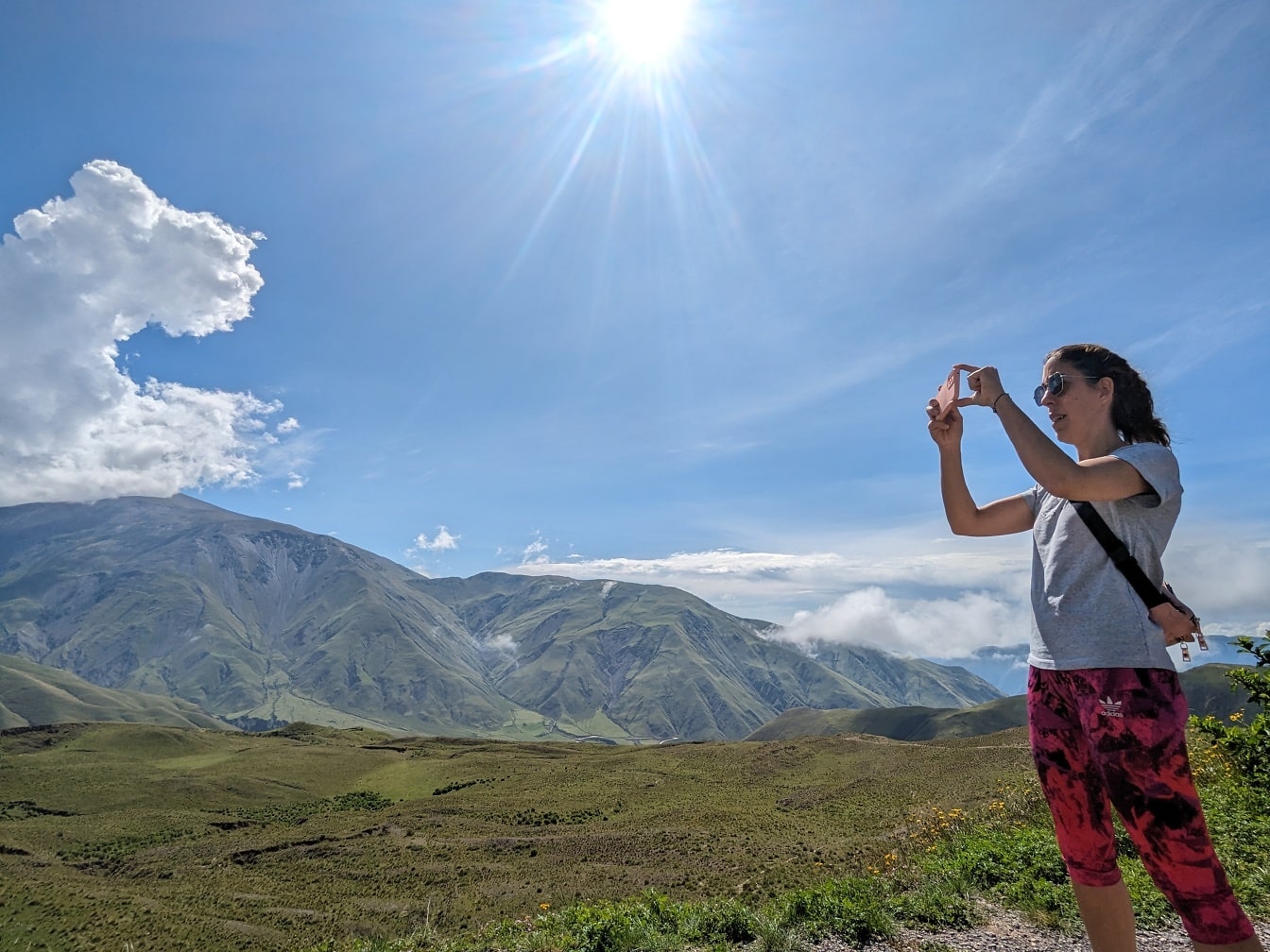 Nainen ottamassa kuvaa vuoresta kännykällään