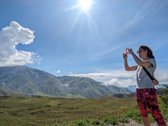 Женщина фотографирует гору на свой мобильный телефон