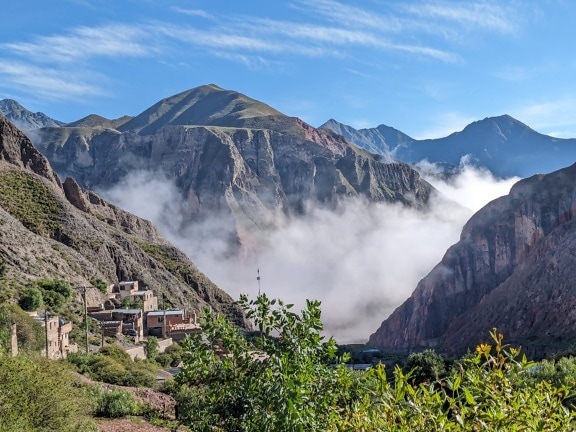 Peisaj montan cu ceață densă care acoperă așezarea rurală din vale