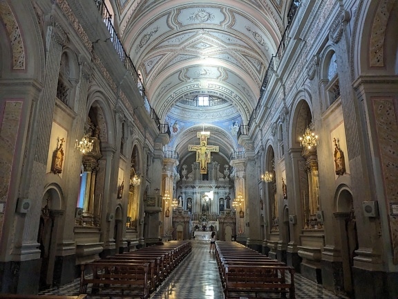 Interior of Salta basilica with many benches and with Jesus Christ on a cross above altar