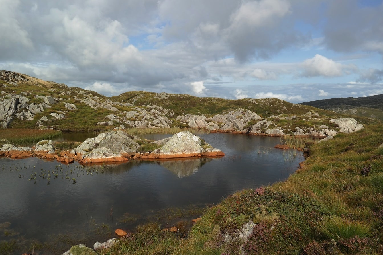 Het landschap van Noorwegen met meer in bergen met klein rotsachtig eiland erin