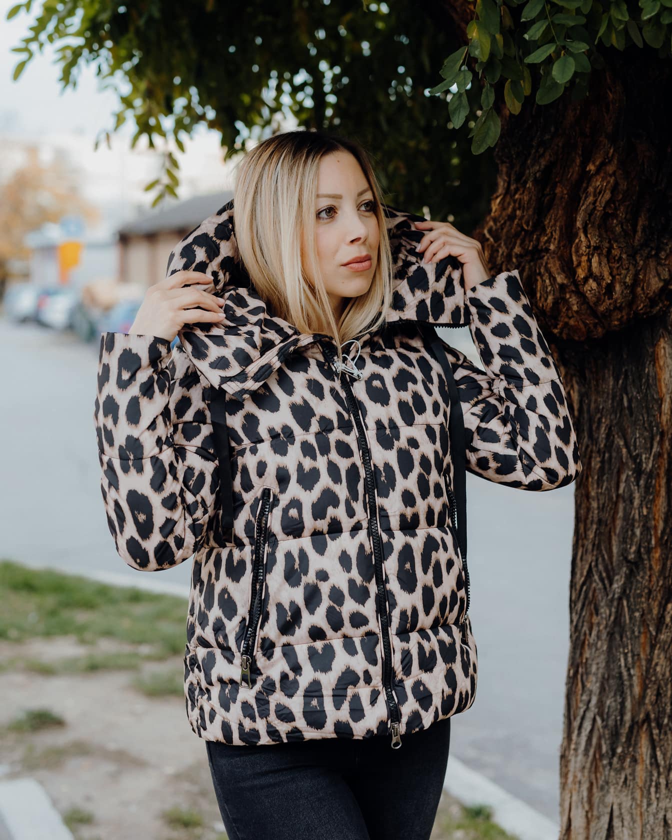 Женщина-фотомодель в современной куртке с рисунком из шкуры леопарда