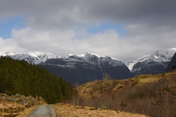 Road in valley of snowy mountain peaks in natural reserve in Norway