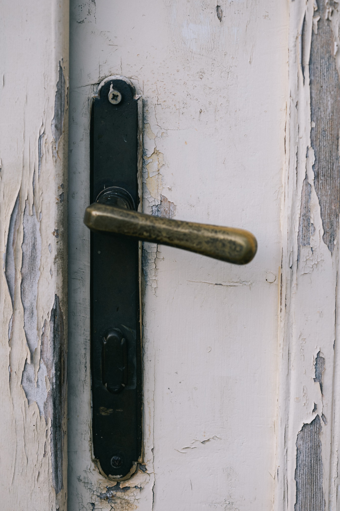 Rustikk dørhåndtak i metall på en hvit dør