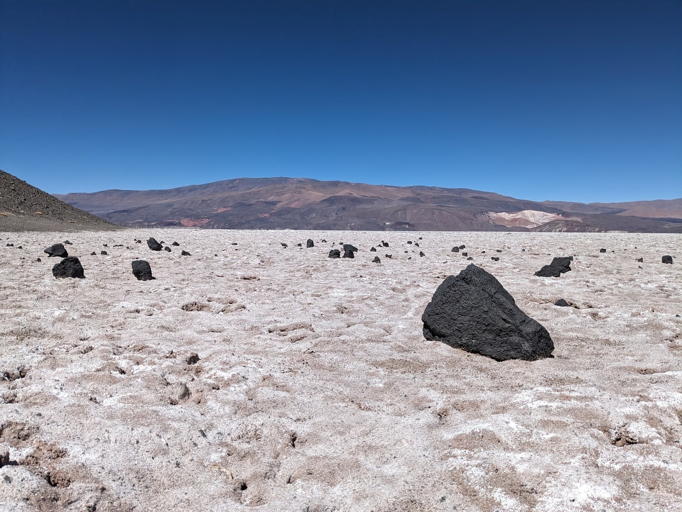 사막의 흰 소금 퇴적물에 검은 화산암이 있는 바위 풍경