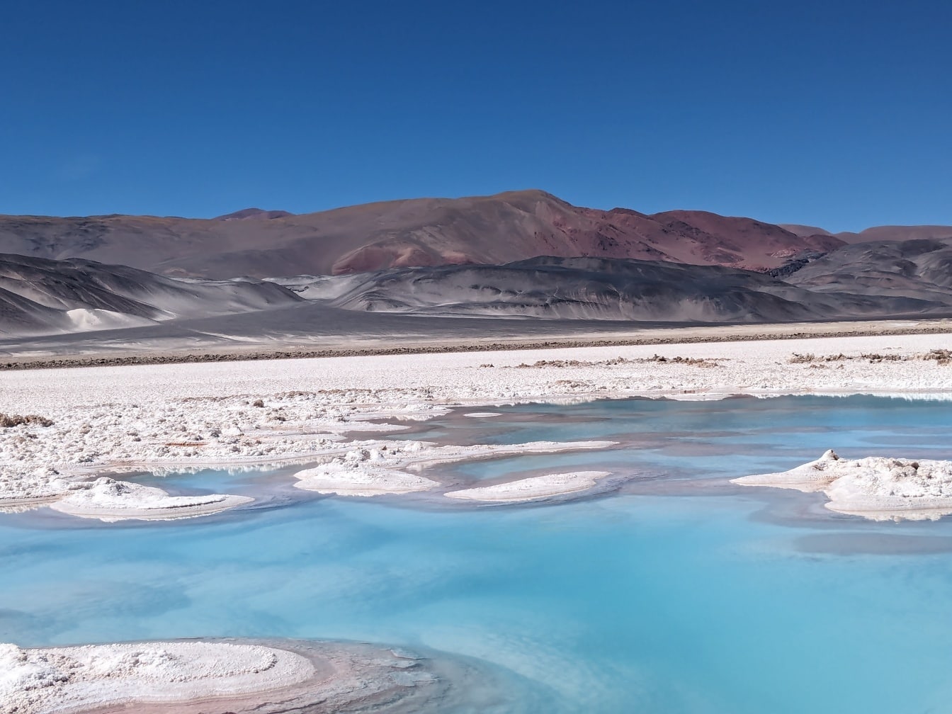 안데스 산맥의 카타마르카 사막에 있는 Salar de Antofalla의 소금 고원에 있는 소금 오아시스 땅에 소금이 쌓여 있습니다.