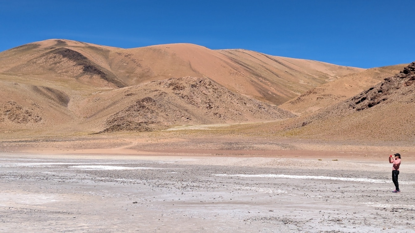 Turista áll a sivatagi hőségben és fényképezi az Atacama-sivatag fenséges táját