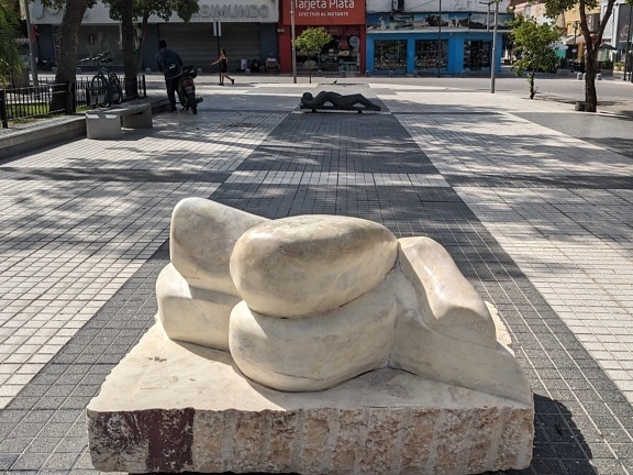 White stone sculpture of a woman’s body at street