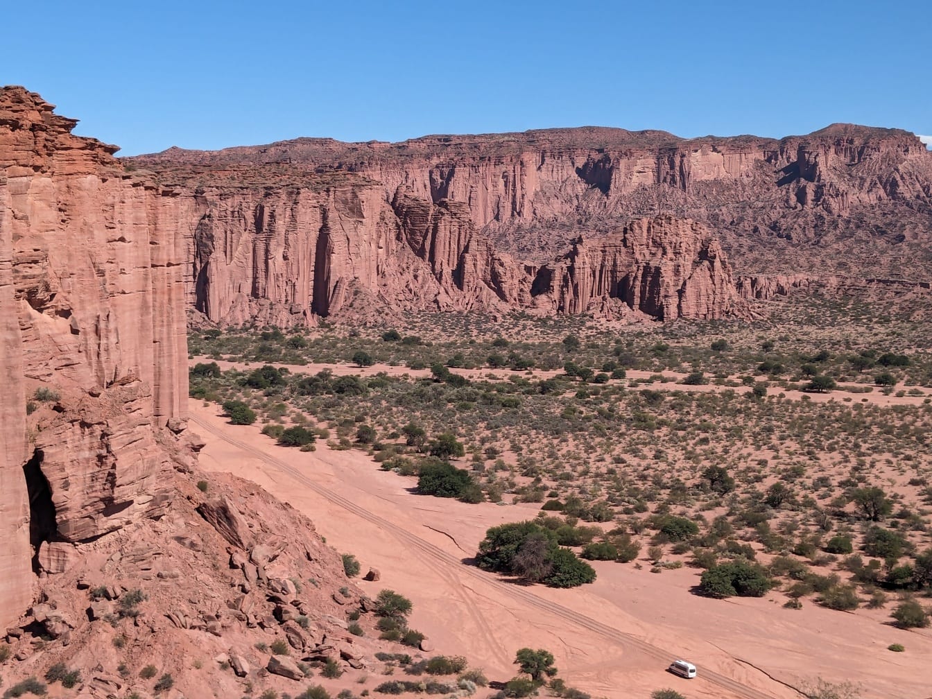 Une vue aérienne d’un paysage désertique avec une route poussiéreuse et de grandes falaises au loin