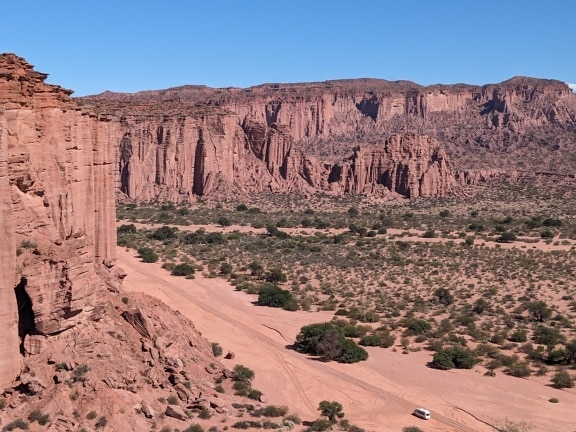 Μια εναέρια άποψη του τοπίου της ερήμου με ένα σκονισμένο δρόμο και ένα μεγάλο βράχο σε απόσταση