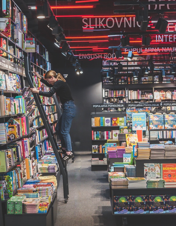 A librarian climbing up a ladder in a book store