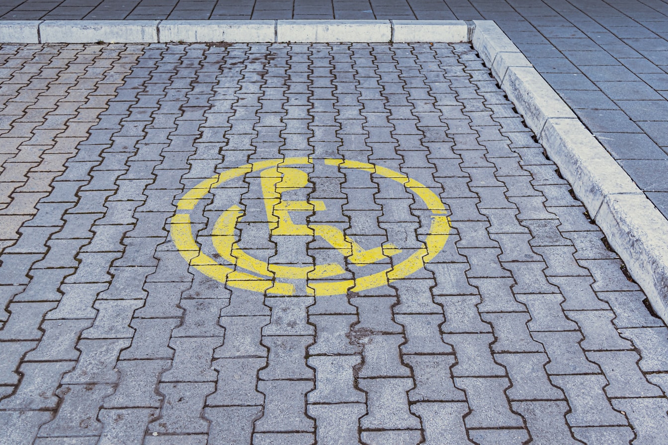 Estacionamiento con un símbolo amarillo de silla de ruedas, una señal de estacionamiento para discapacitados