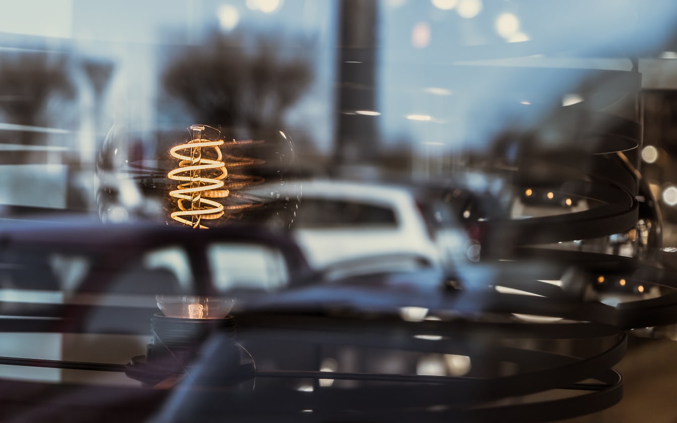 Rustik glödlampa i ljuskrona fotograferad genom fönsterglas