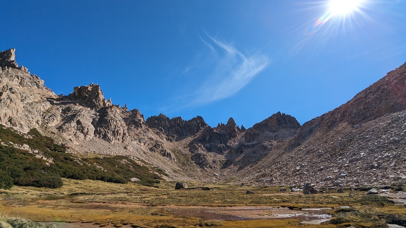 Felsige Berge im Naturreservat Nahuel Huapi mit einem Bach im Tal und sonnigem blauem Himmel