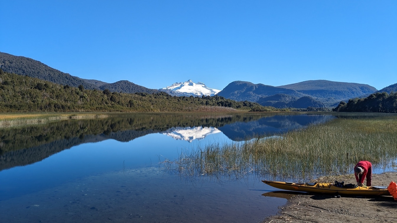 アルゼンチンのナウエル・ナピ国立公園にあるリオ・ネグロ州パタゴニアのヘス湖のほとりでカヌーを持つ人