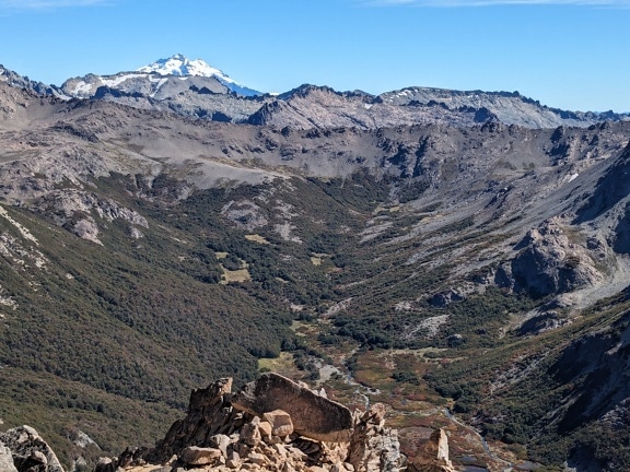 Горный хребет с долиной и заснеженной горой в национальном парке Науэль-Уапи в Южной Америке