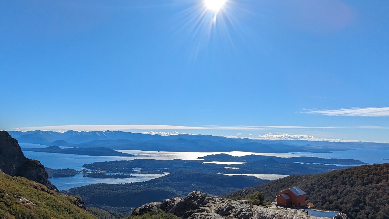 Casă de munte pe un deal cu apă și munți pe malul lacului Nahuel Huapi din Patagonia, Argentina