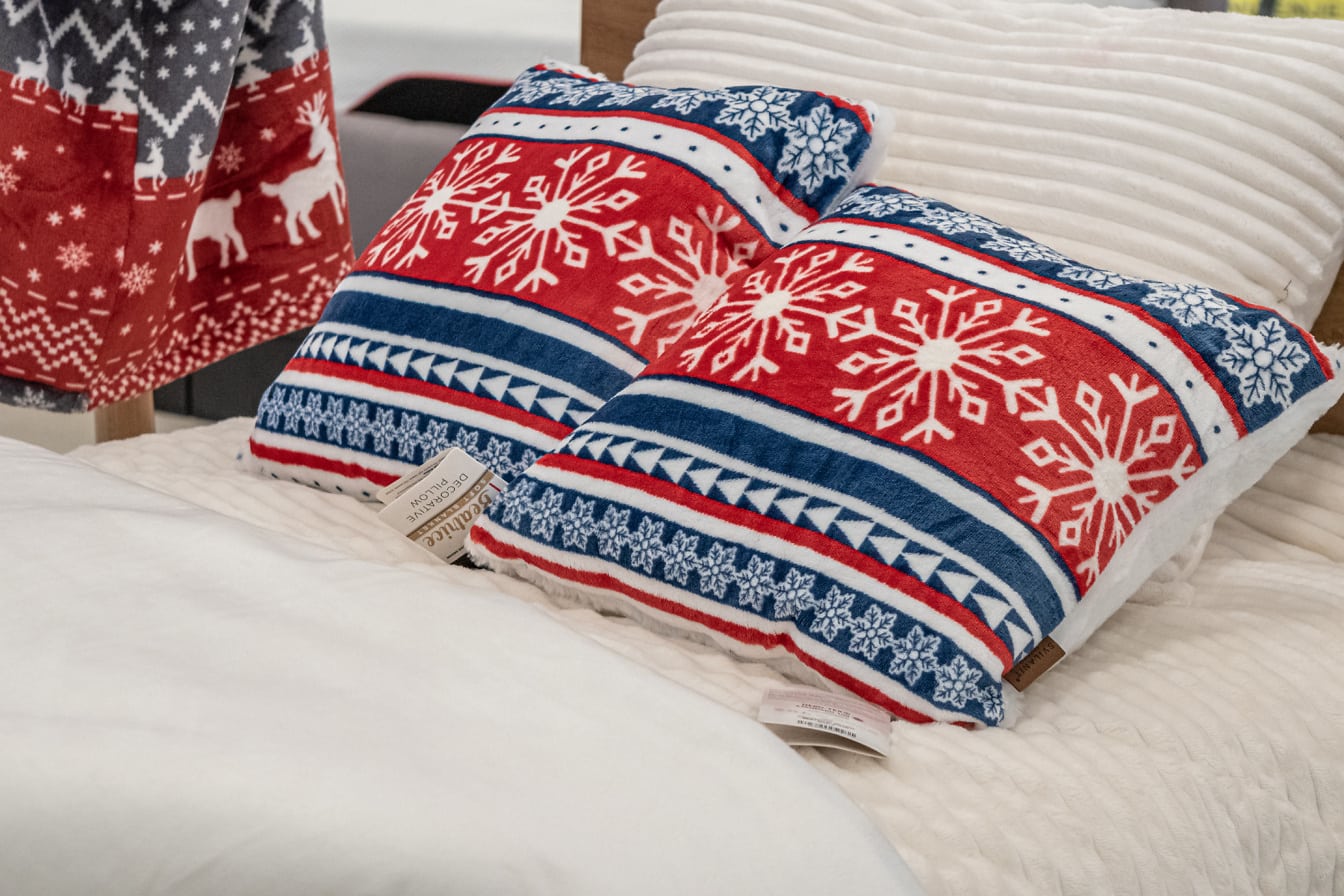 Rood-blauwe kussens met nieuwjaarsmotieven op een bed