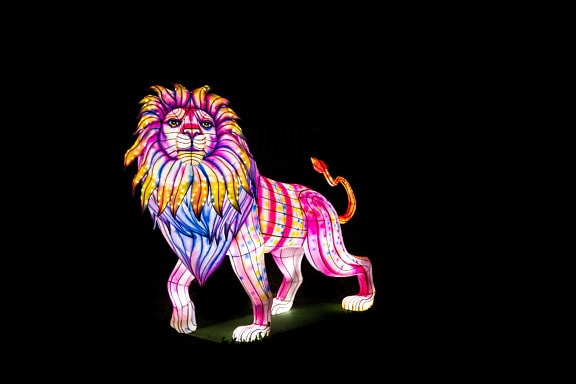 A colorful lit statue of a lion at night