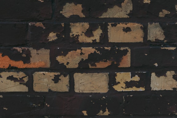 Texture of a brick wall painted with black paint that peels off