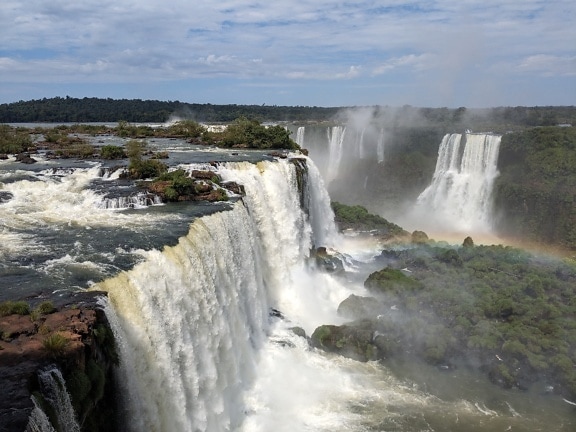 A foggy rainbow on waterfalls of the Iguazu river in natural park on border of Argentina and Brazil