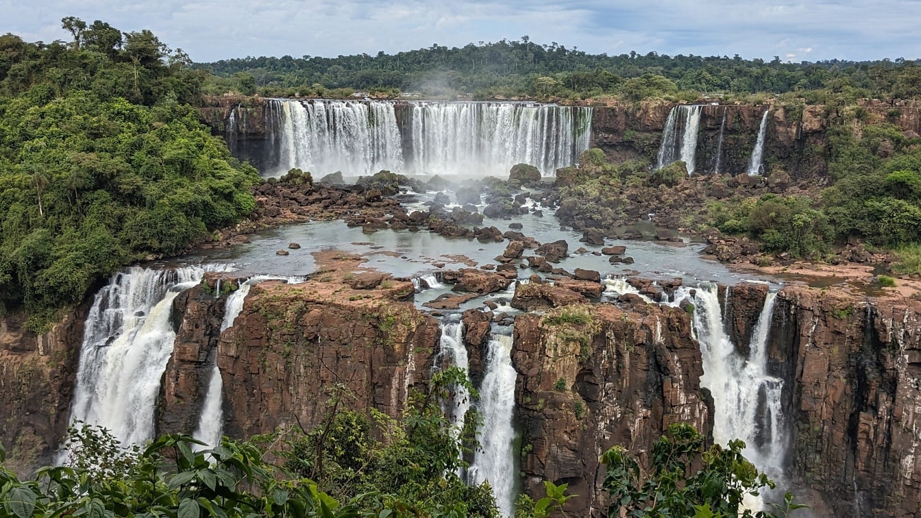 Arka planda yağmur ormanları olan Patagonya’daki bir doğal parkta basamaklı şelale ile Iguazu Nehri
