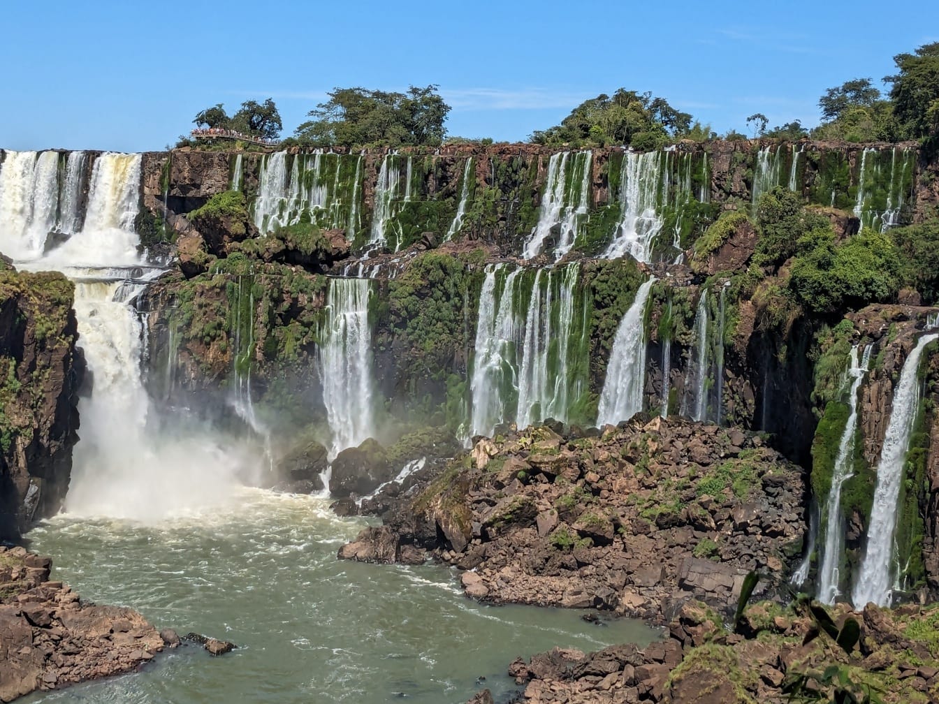 Pemandangan indah sungai Iguazu dengan air terjun dan pepohonan hijau di tebing