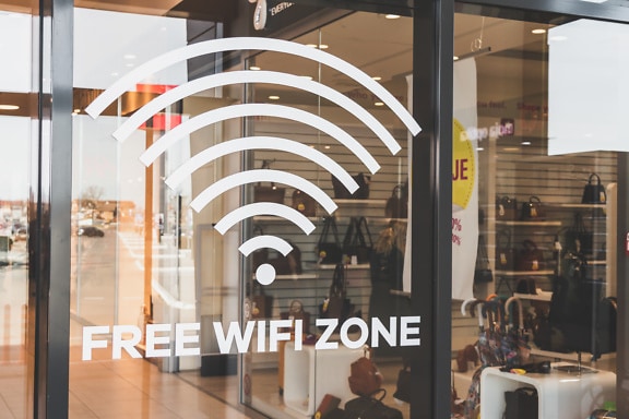 Sign of free wifi zone on the glass window of the store inside the shopping center