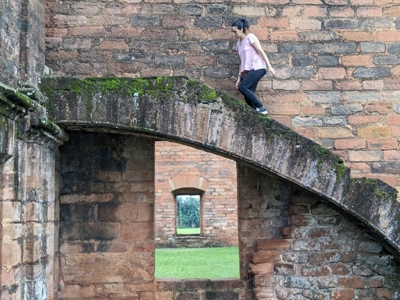 En kvinde klatrer op ad en stenbuet trappe over et vindue med udsigt over et andet vindue