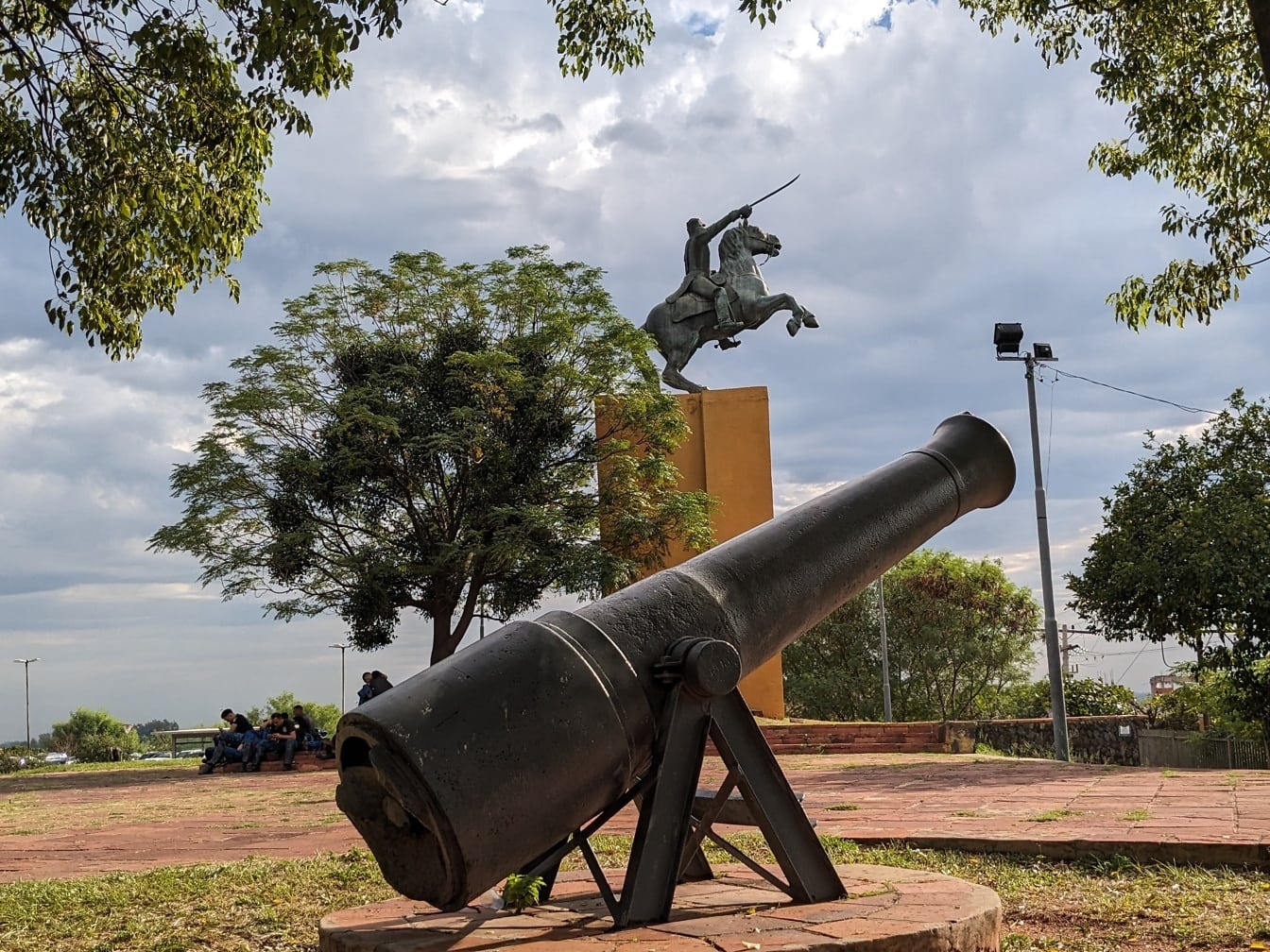 Beeldhouwwerk van een kanon en een standbeeld van een man op een paard in het Overwinningspark in Asuncion, een hoofdstad van de republiek Paraguay