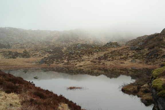 ノルウェーの霧のかかった岩の丘を背景にした山湖