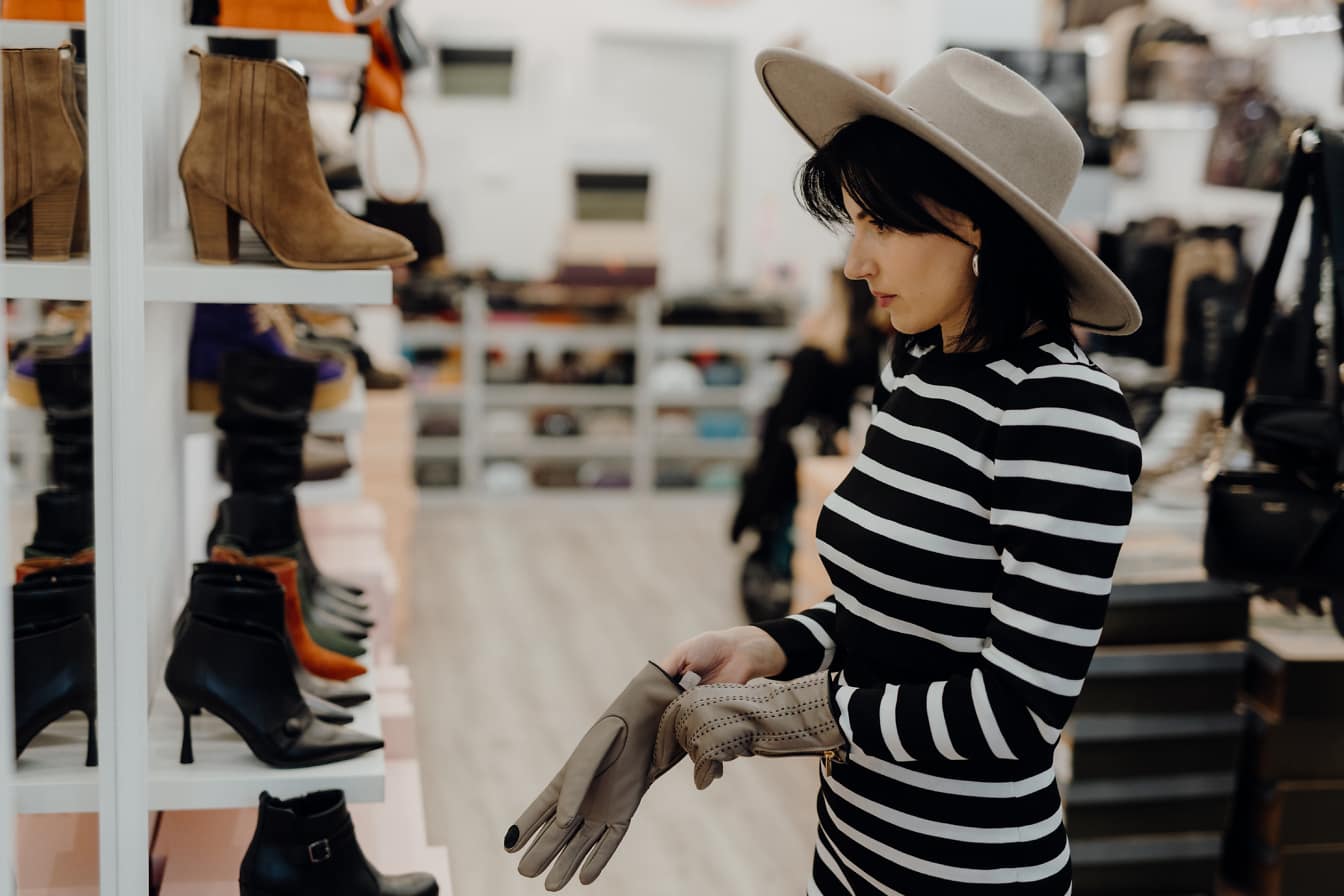 Một người phụ nữ thử mũ và găng tay trong một cửa hàng quần áo và giày dép