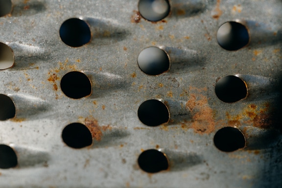 Texture of rusty galvanized steel surface of hand grater with holes