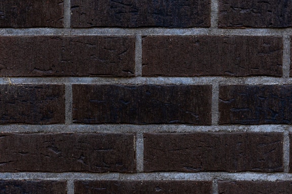 Texture of horizontally stacked dark brown rustic brick with white cement