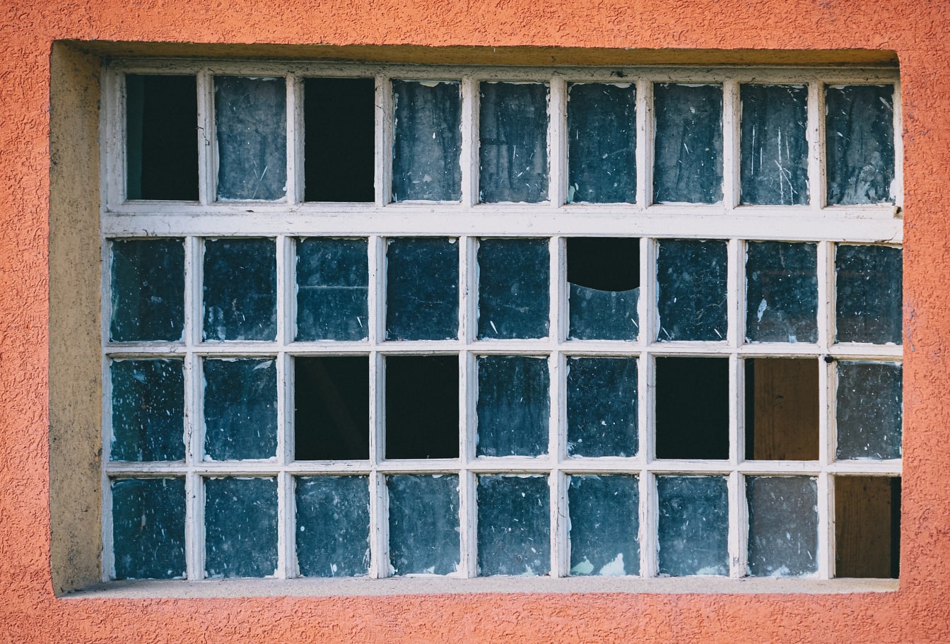 Een oud raam met veel kleine kozijnen en gebroken glas