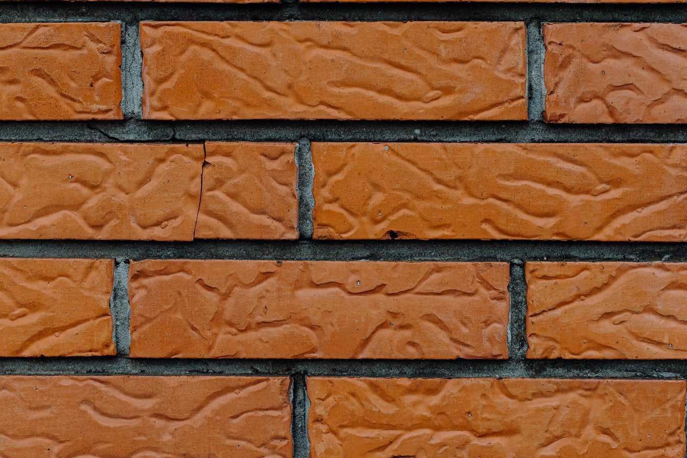 Tekstur dinding bata dengan fasad kemerahan yang ditumpuk secara horizontal, batu bata dan semen gelap