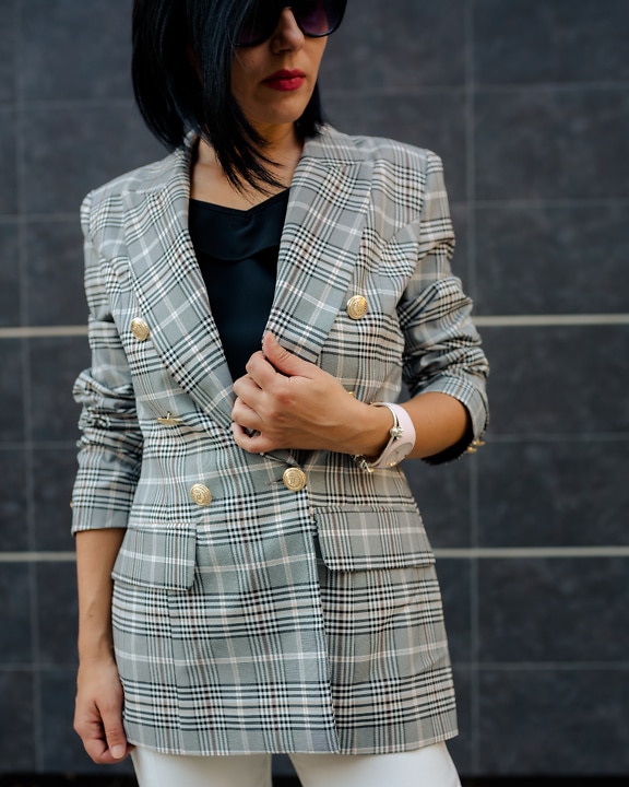 Slender handsome young businesswoman in checkered business coat