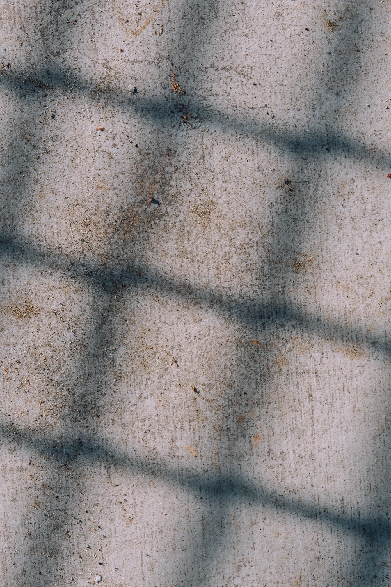 Schaduw in de vorm van een rechthoek op een vuil betonnen oppervlak met vlekken