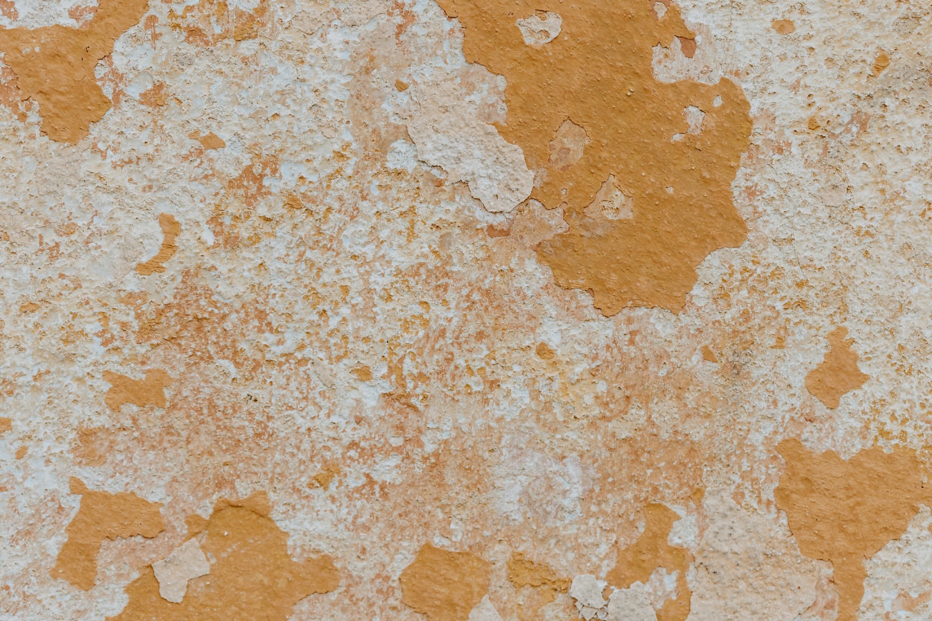 오래된 벽에서 벗겨지는 주황색-노란색 라임 페인트의 질감