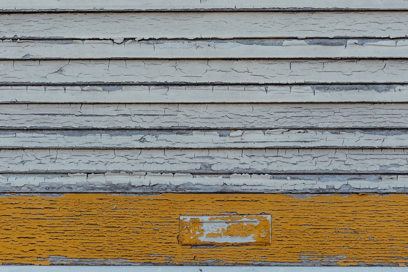 旧木制百叶窗的纹理，带有剥落的旧白色和橙黄色油漆