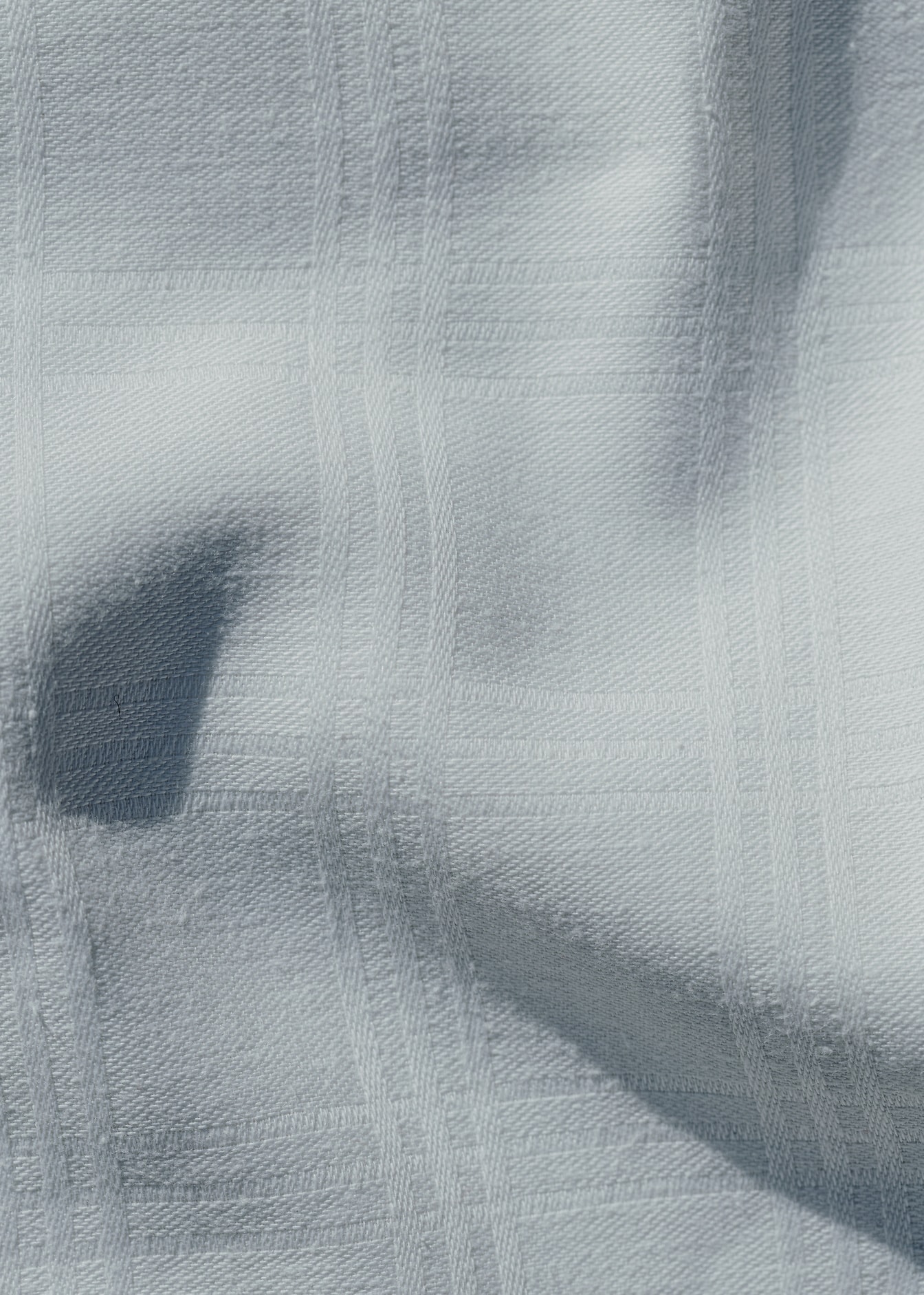 Zbliżenie tekstury pomarszczonej białej tkaniny bawełnianej z prostokątnym wzorem