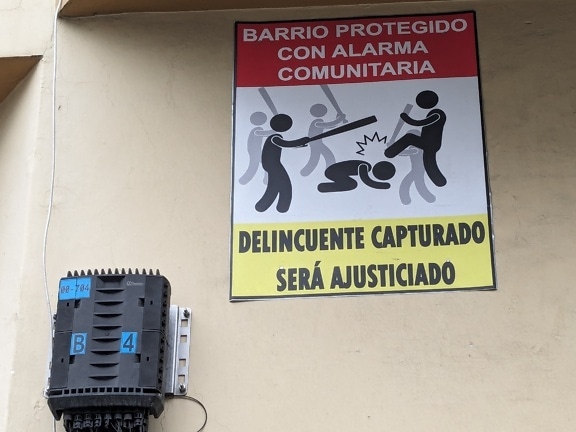 Warning sign against delinquents and bandits with a Spanish-language inscription on the wall
